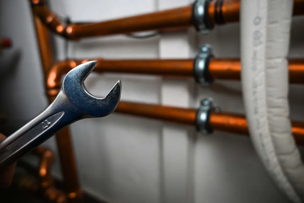 Pipes in a boiler room holding a wrench and repairing copper water pipes in a boiler room.